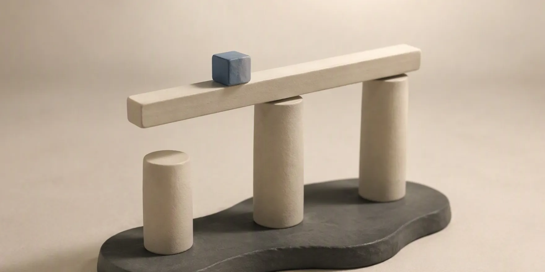 Three off-white cylindrical pillars of different heights on a dark irregular base, with a horizontal beam across two pillars and a small blue cube on the beam.