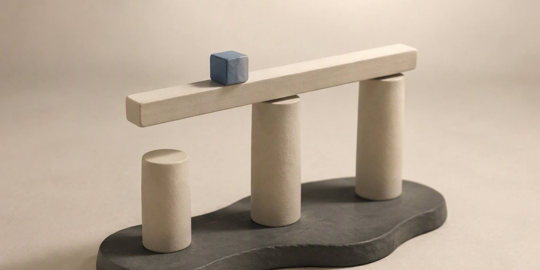 Three off-white cylindrical pillars of different heights on a dark irregular base, with a horizontal beam across two pillars and a small blue cube on the beam.